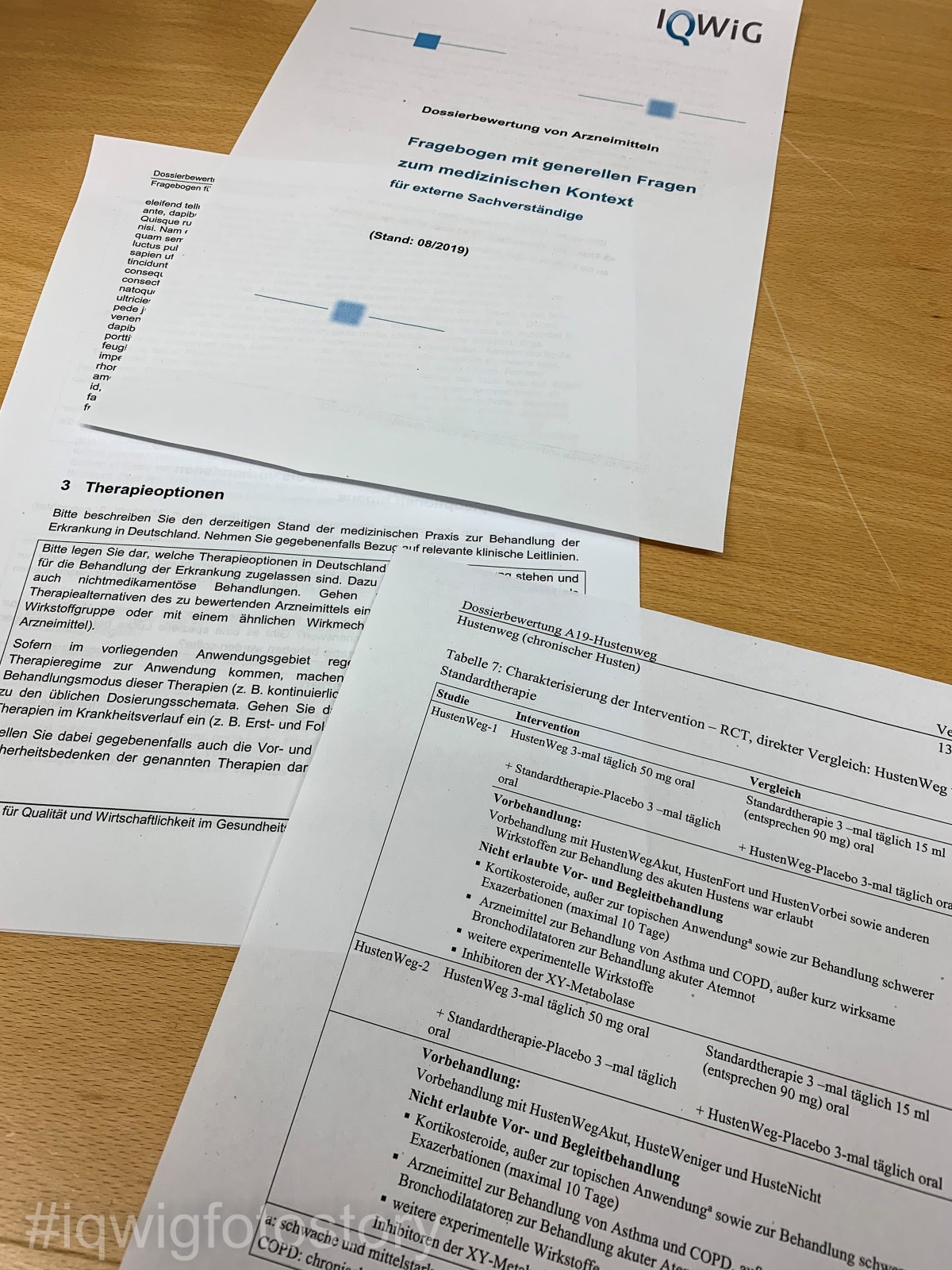 Desk with three sheets of paper: two from the questionnaire completed by the external experts and one from the draft of the dossier assessment describing the treatment in the two clinical studies.