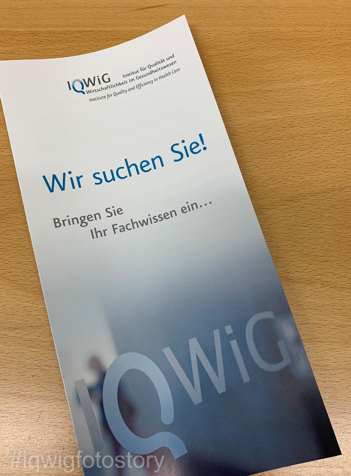 An IQWiG flyer is on a table. It is used to recruit external experts. On the front, it says in large letters, “We are looking for you!”